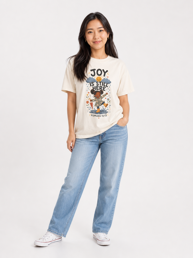 Joy Is Still Here Romans 15:13 Christian tee in Ivory, full-body view