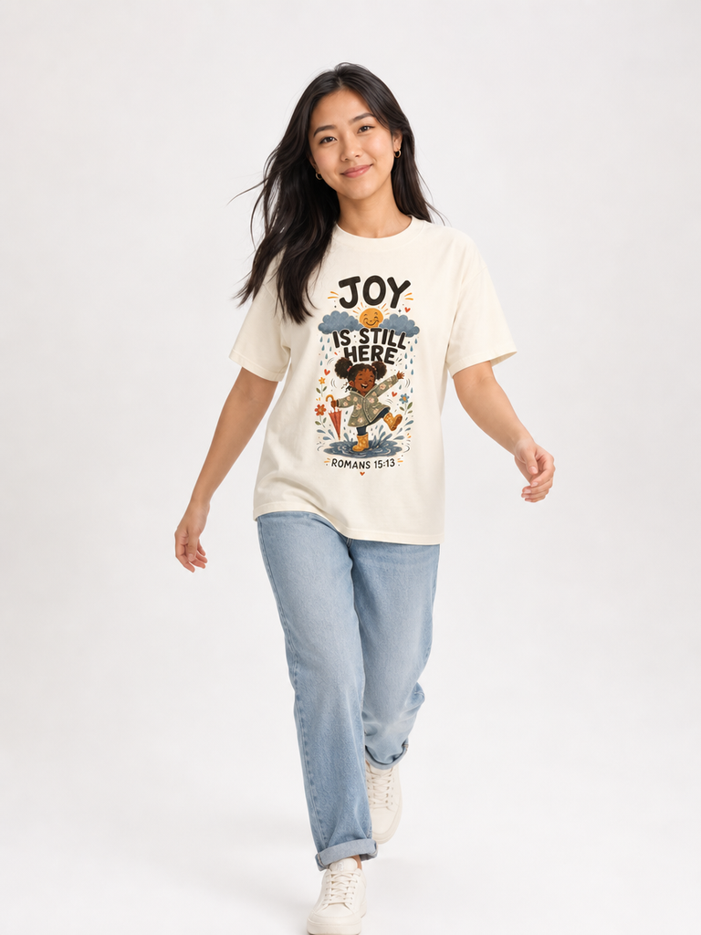 Joy Is Still Here Romans 15:13 Christian tee in Ivory, walking view