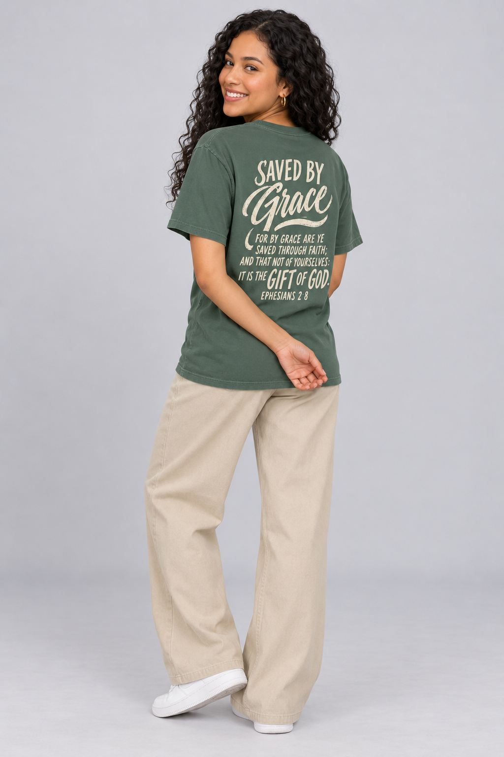 Woman wearing the Blue Spruce Saved By Grace Tee in a shoulder-turn back pose.