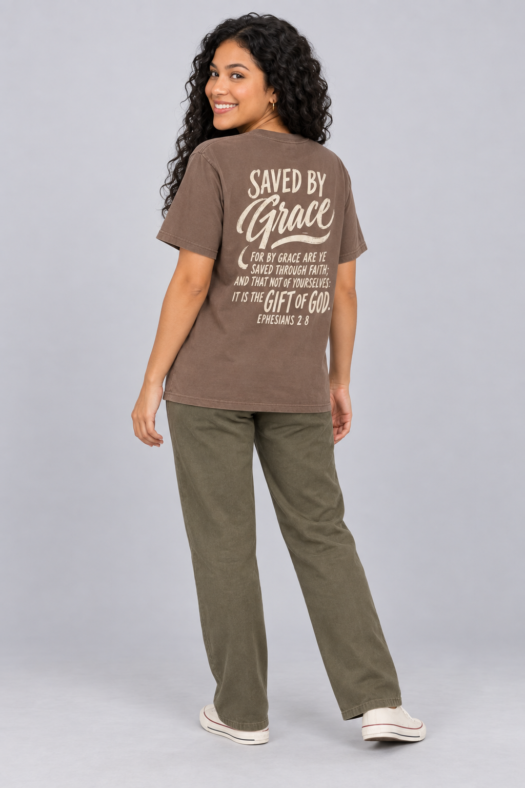 Woman wearing the Espresso Saved By Grace Tee in a shoulder-turn back pose.