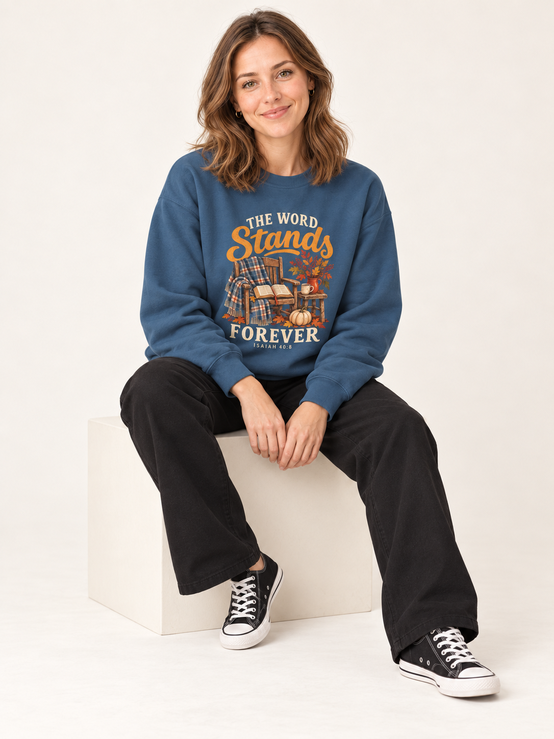 The Word Stands Forever sweatshirt in Indigo Blue — seated cube on a model