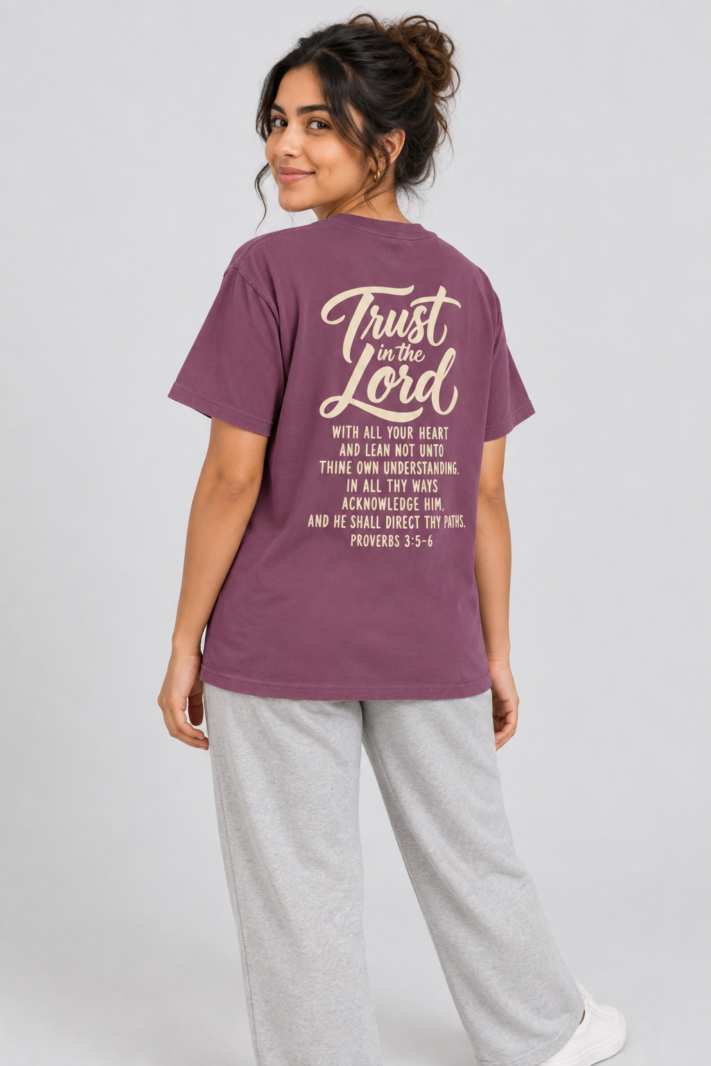 Woman wearing the Berry Trust In The Lord Tee in a shoulder-turn back pose.