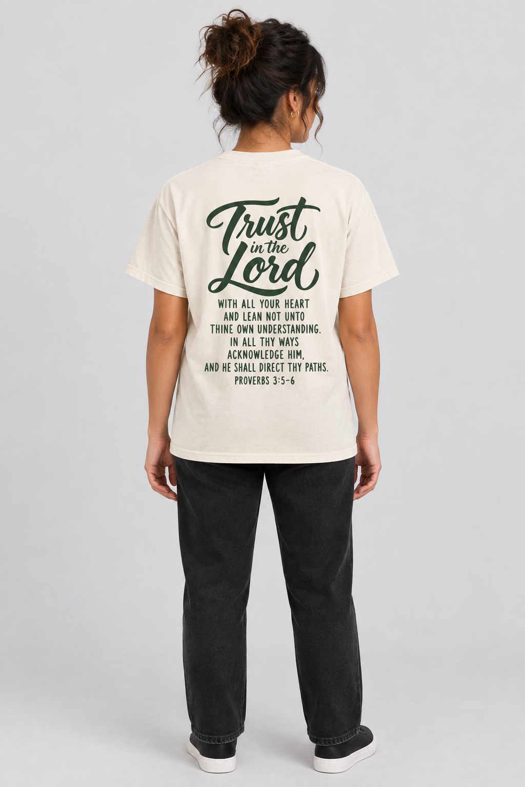 Woman wearing the Ivory Trust In The Lord Tee in a full back pose.