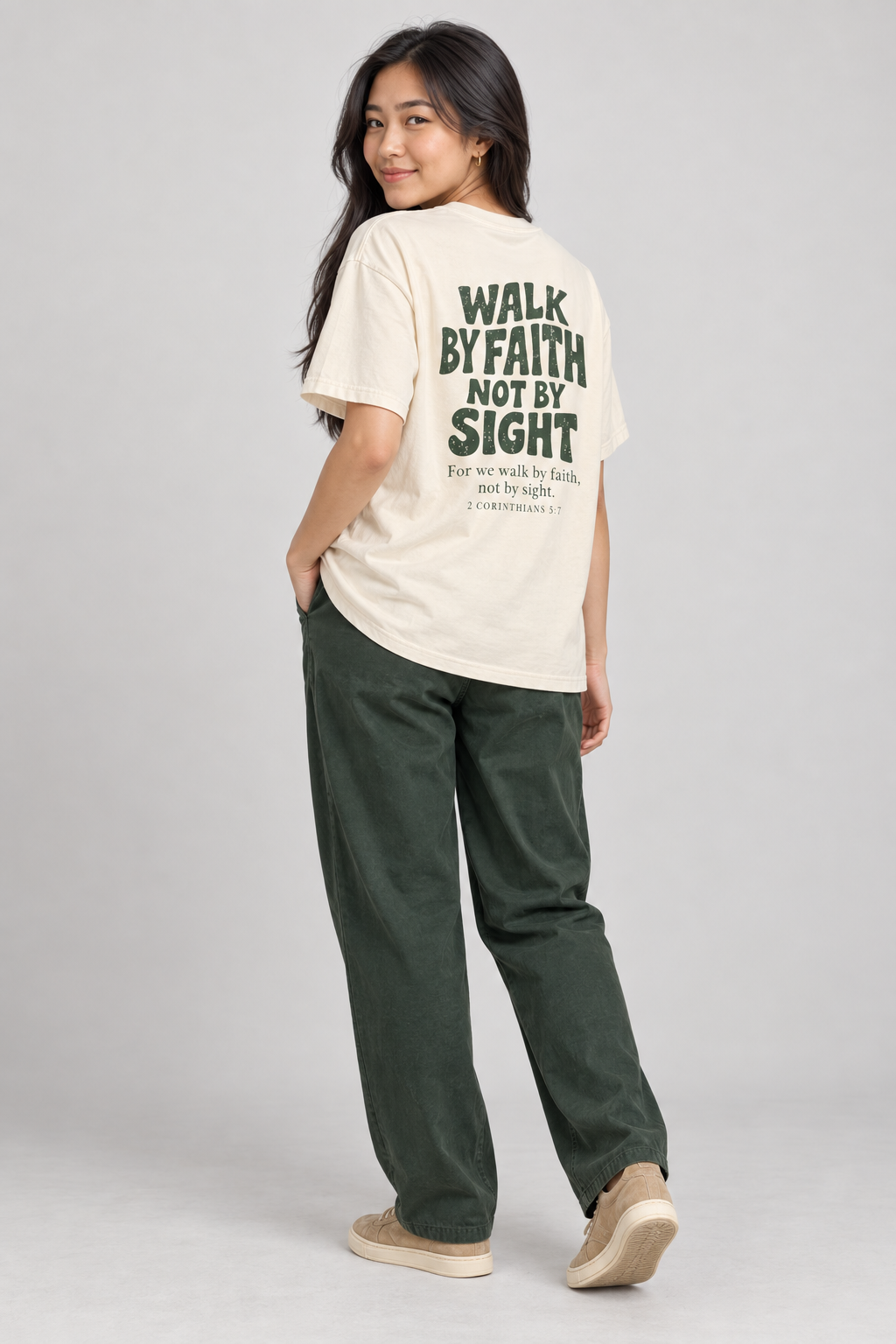 Woman wearing the Ivory Walk By Faith Tee in a shoulder-turn back pose.