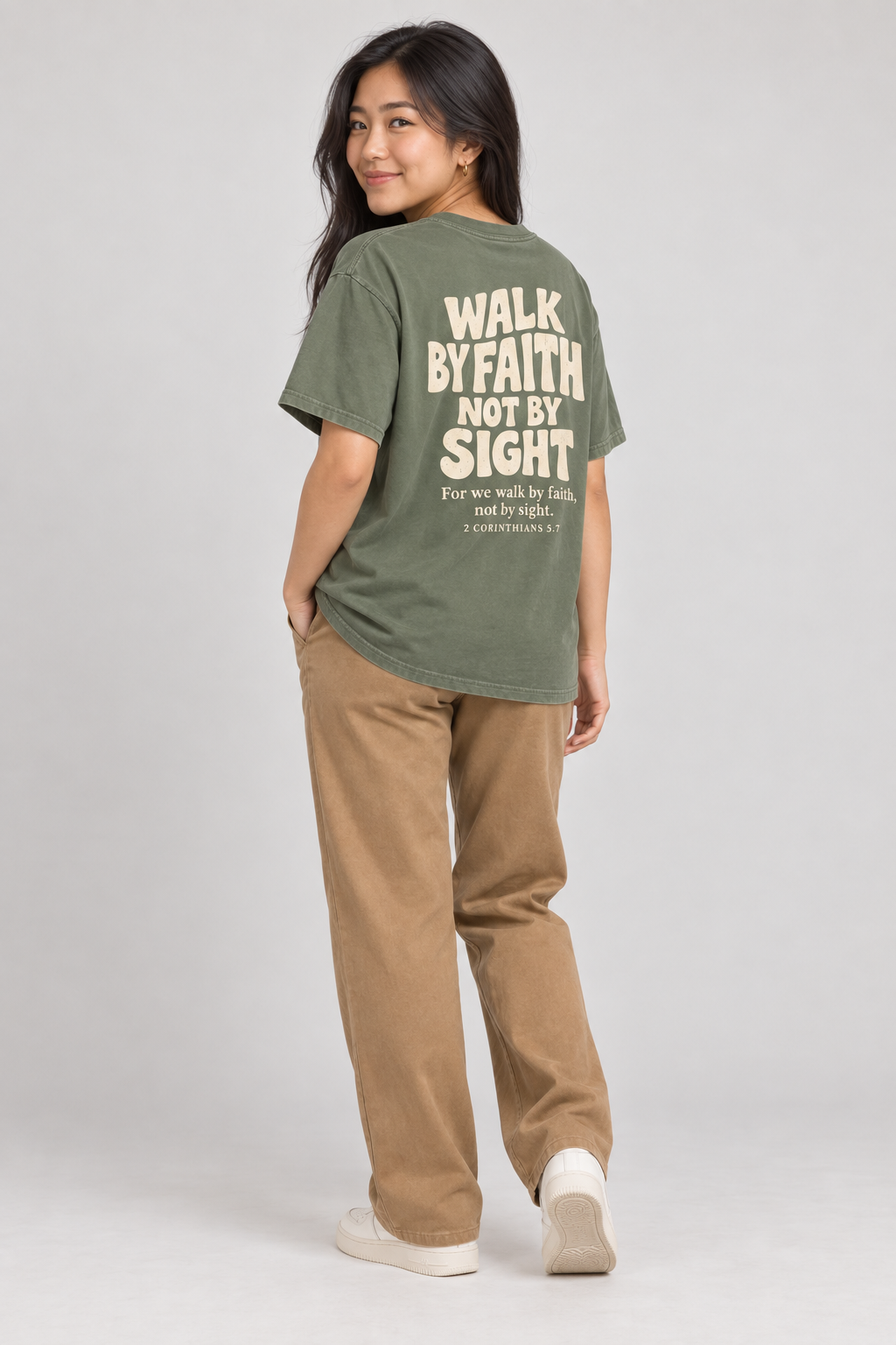 Woman wearing the Moss Walk By Faith Tee in a shoulder-turn back pose.