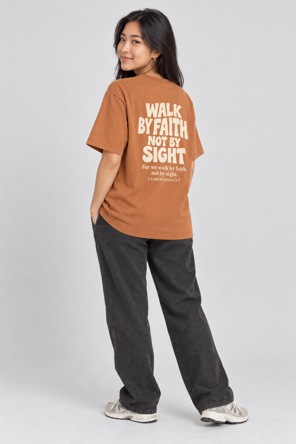 Woman wearing the Yam Walk By Faith Tee in a shoulder-turn back pose.