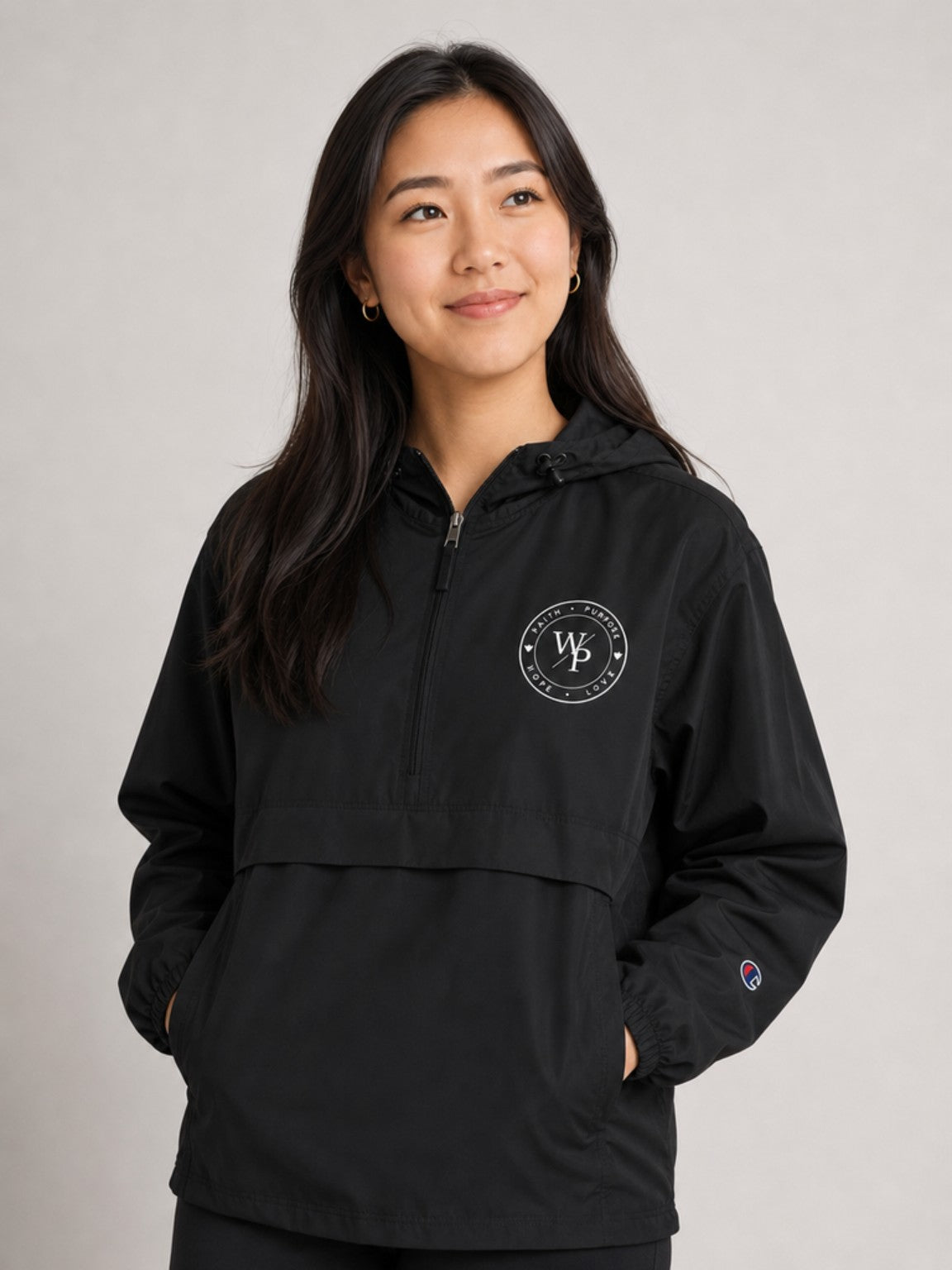 Woman looking up while wearing black Worn with Purpose Champion packable anorak, featured close-up
