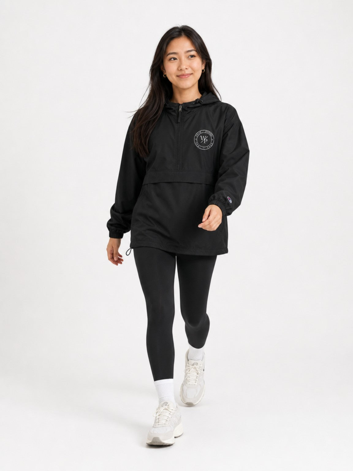 Woman wearing the black Worn with Purpose Champion packable anorak jacket, walking lifestyle view