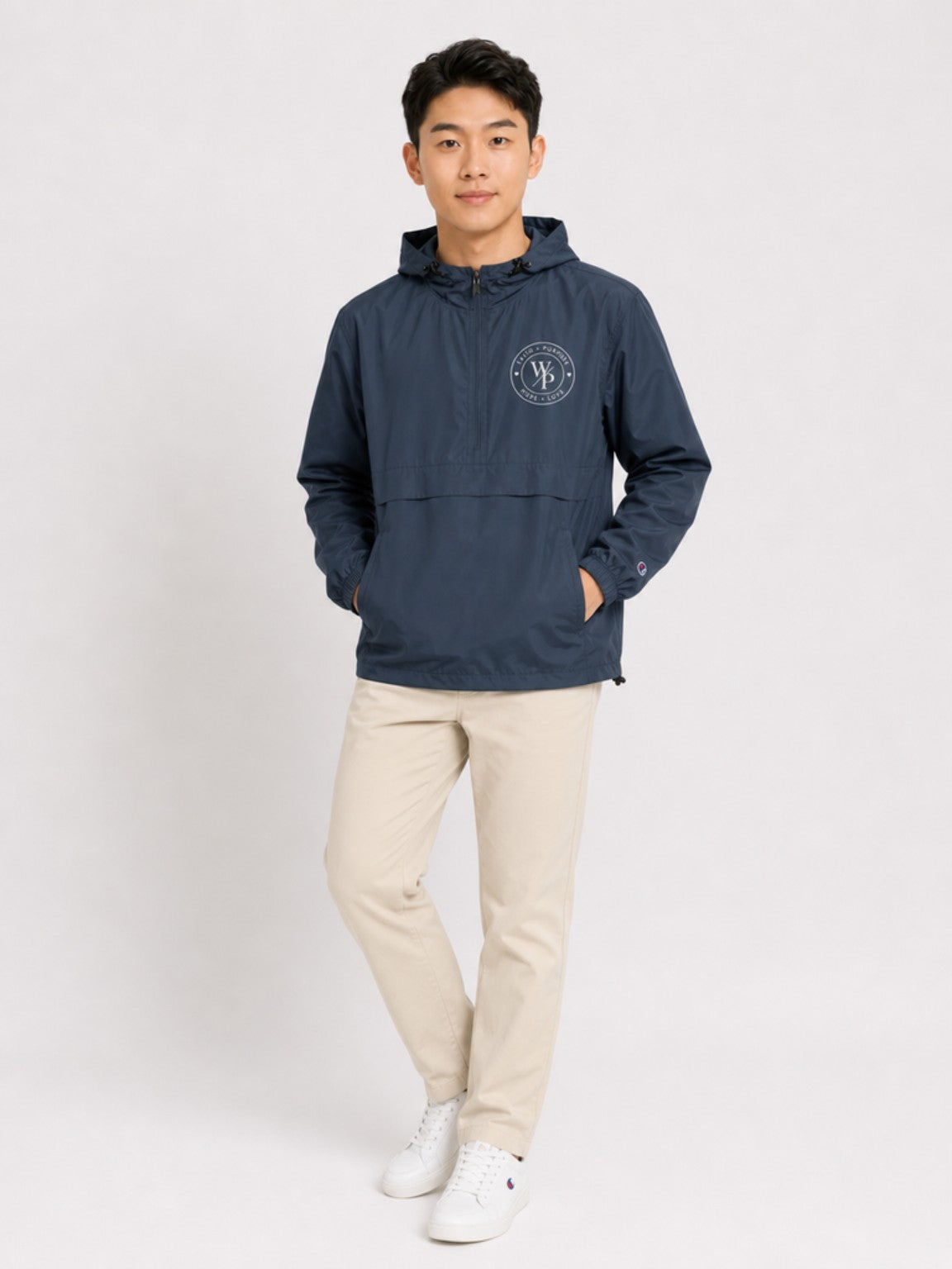 Man wearing the navy Worn with Purpose Champion packable anorak jacket with neutral pants