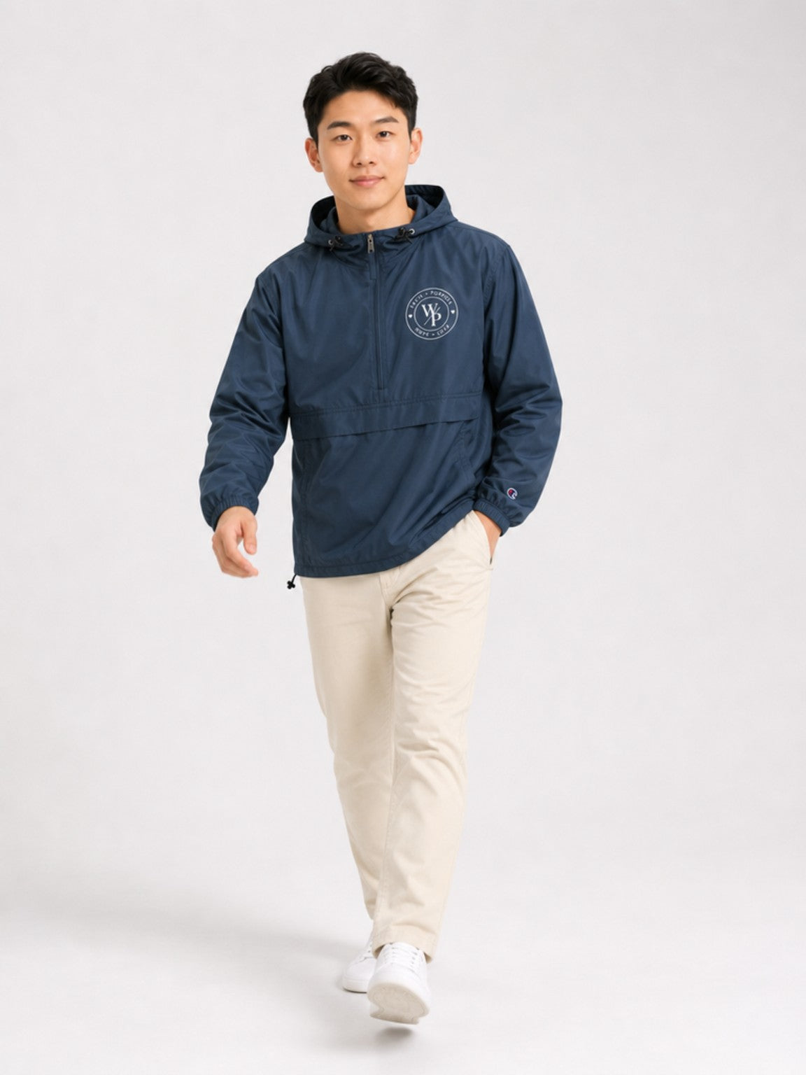 Man wearing the navy Worn with Purpose Champion packable anorak jacket, walking lifestyle view
